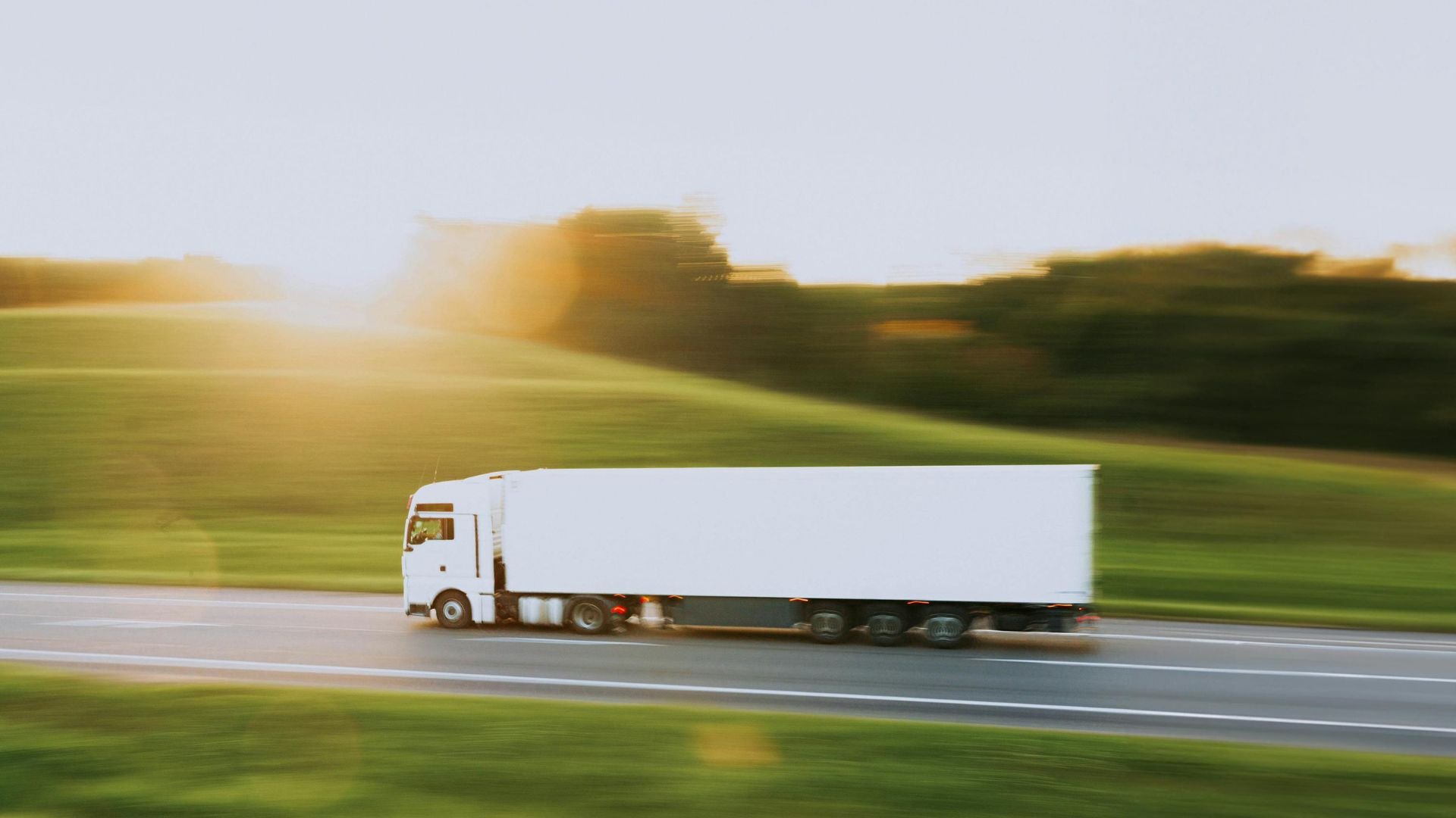 White truck speeding on highway with blurred green landscape background