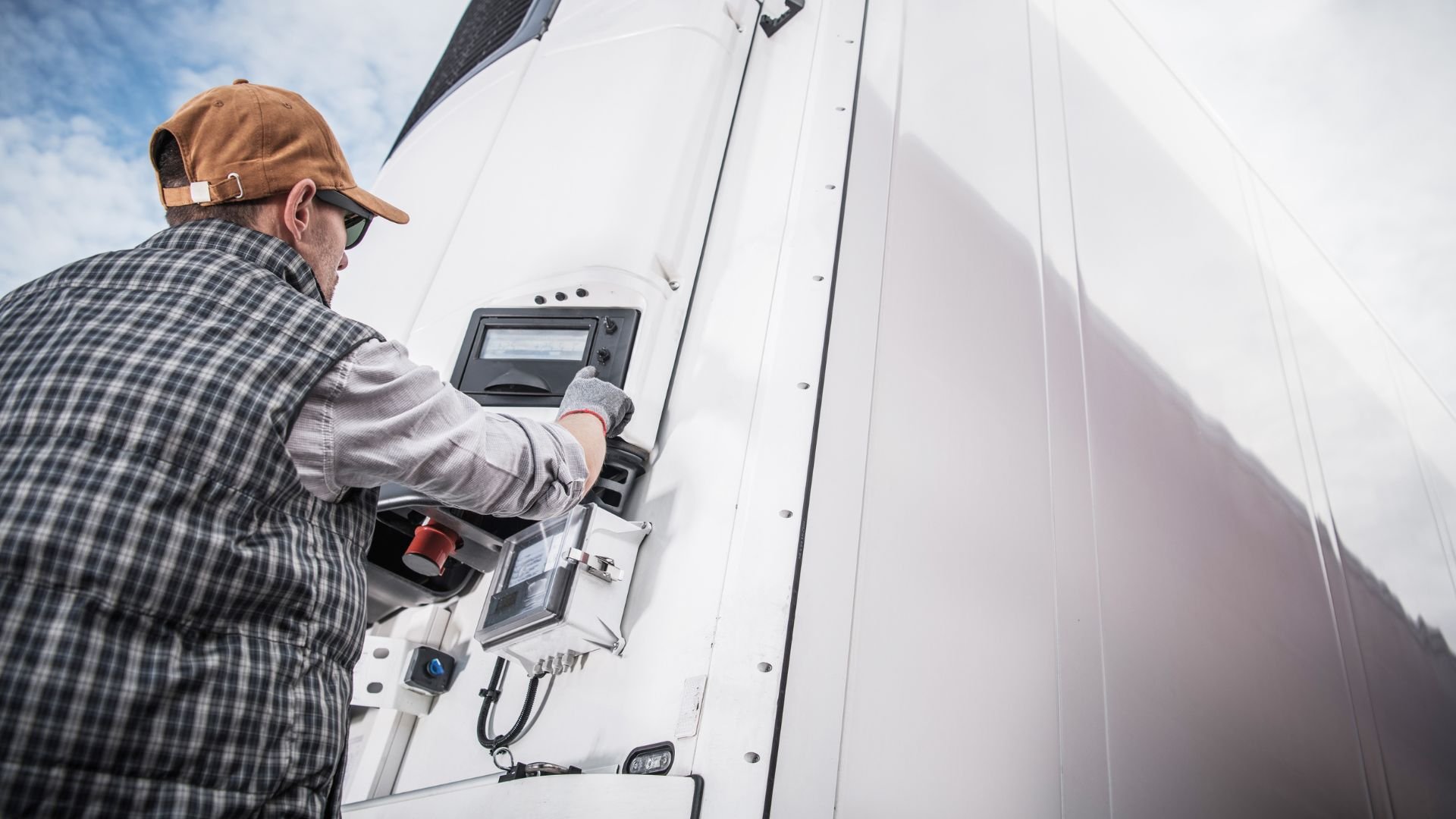 Technician in cap checking industrial equipment control panel on white wall